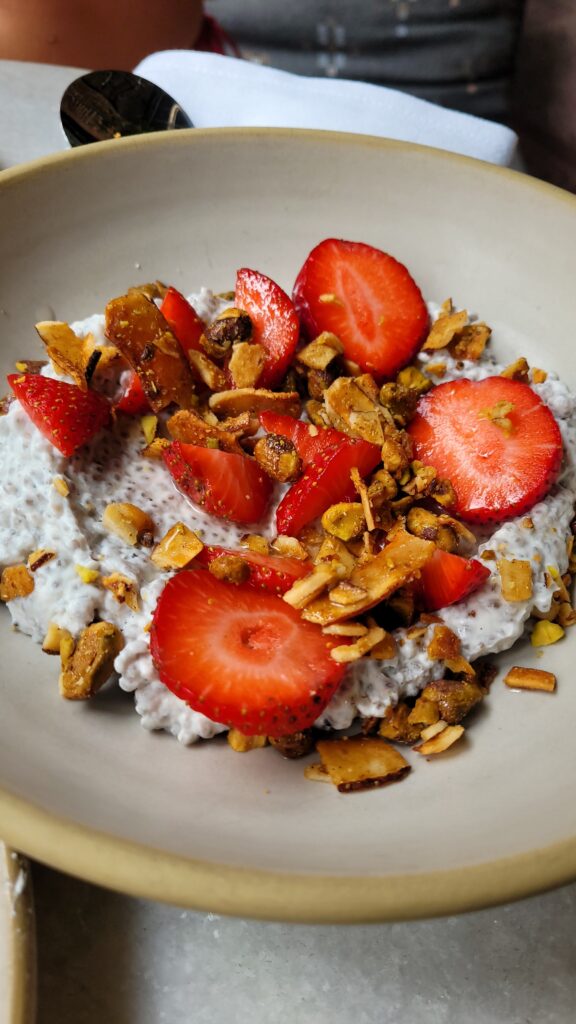 A bowl of chia pudding topped with fresh strawberries, granola, and nuts at Bath House